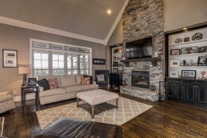 Two-story living room with stone fireplace and built-in cabinetry